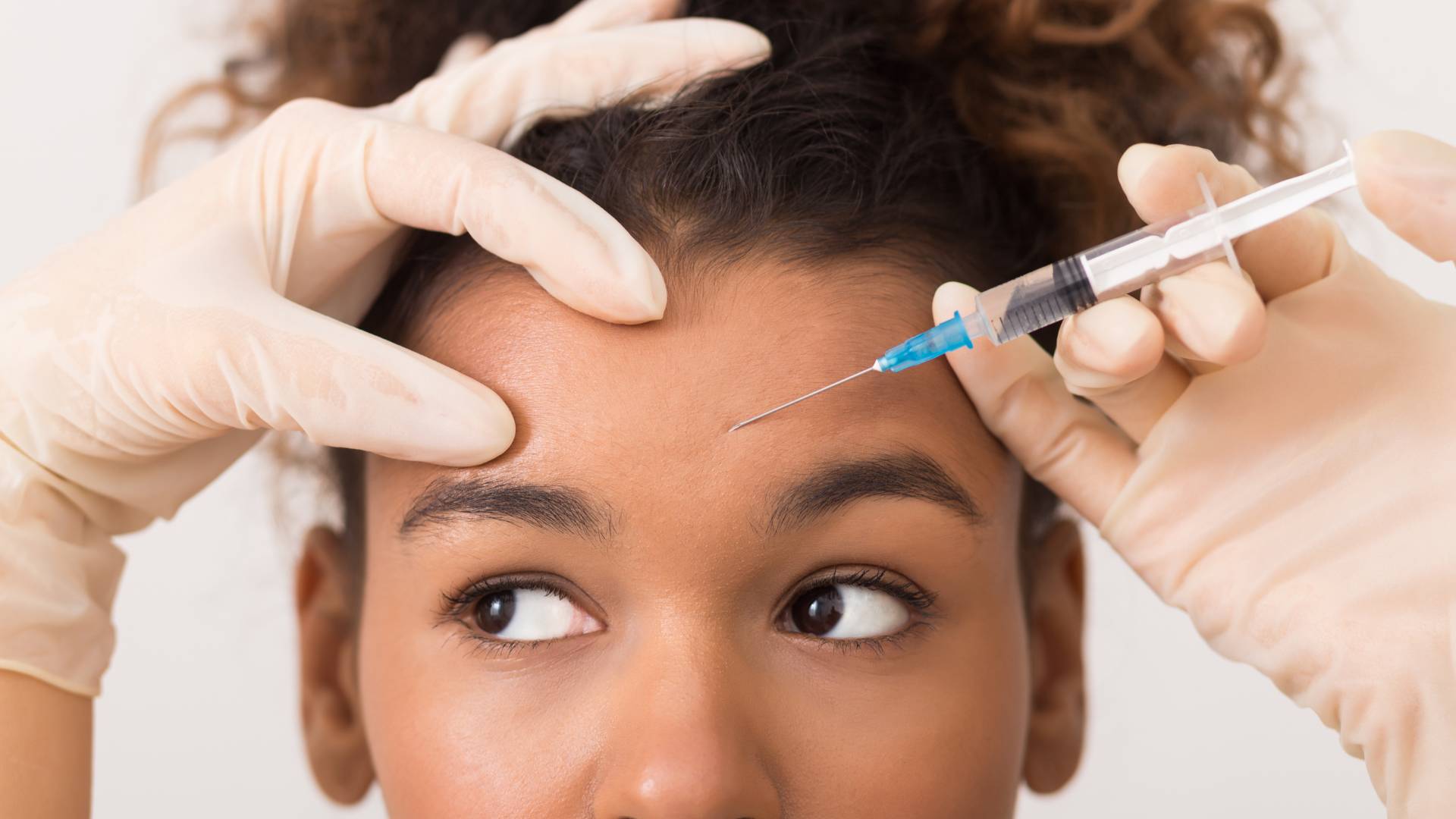 African-american woman getting botox injection in forehead