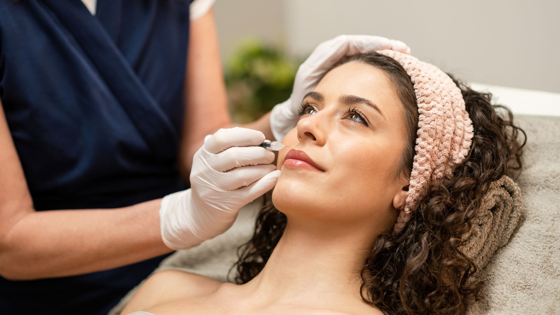 beautician injecting filler into lips of female client