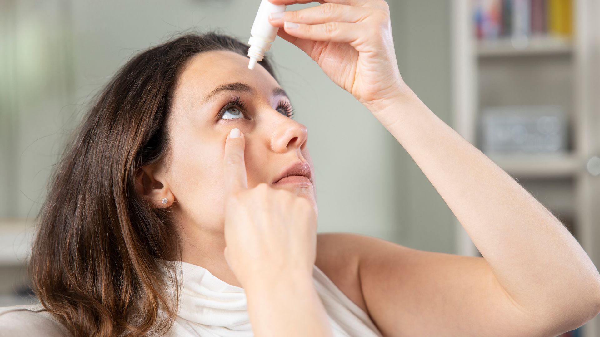 Young woman putting eye drops 