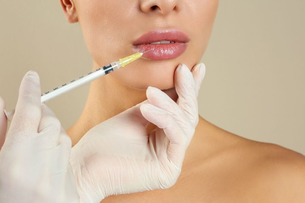 Woman getting lip injection on beige background closeup, related to lip filler cost