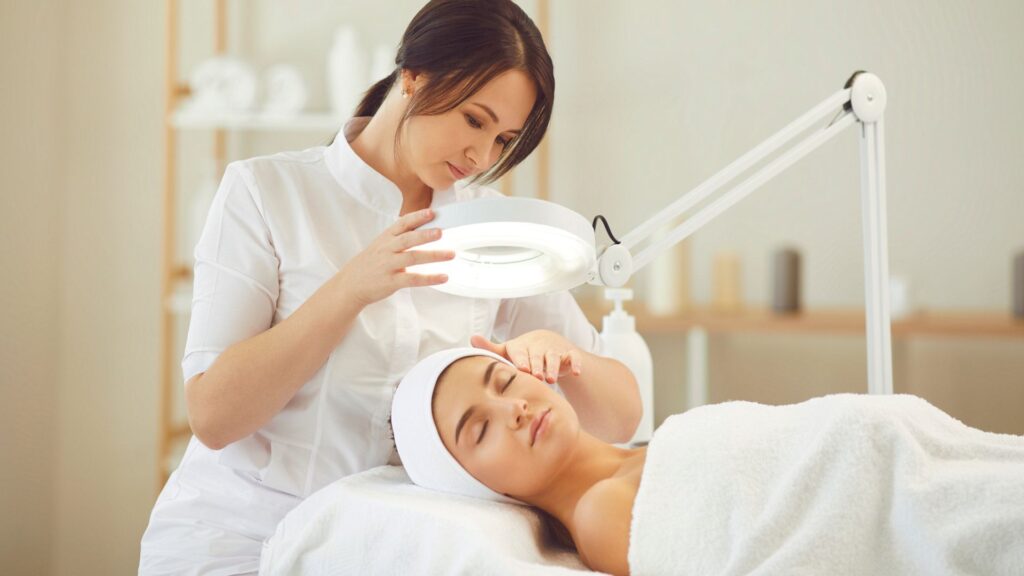 A relaxed young woman receiving professional skincare procedures performed by a nurse injector in a modern beauty salon, highlighting the comfortable aesthetic experience.